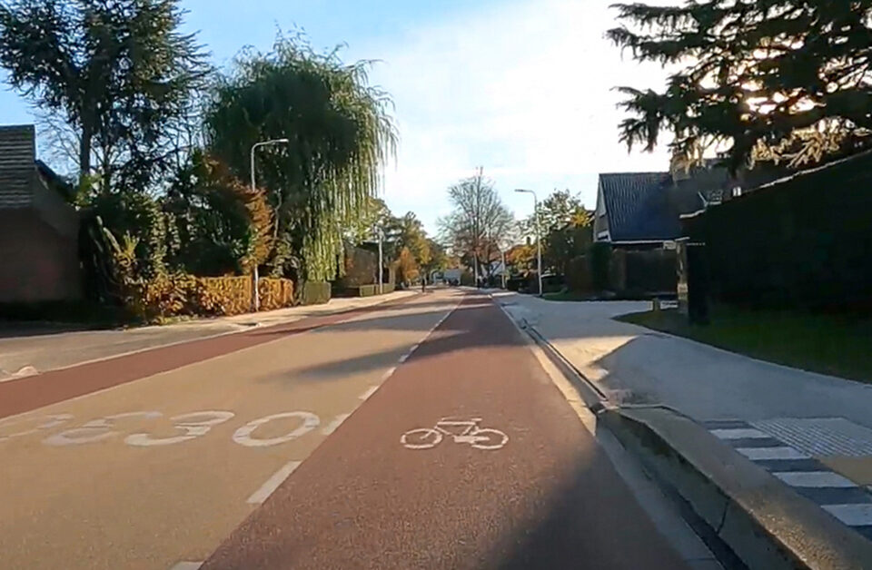 Een weg ingericht als een GOW30 met een geel geasfalteerde rijbaan en aan beide kanten een rode fietsstrook.